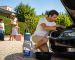 Homme vérifiant le moteur de sa voiture avant un départ en vacances, famille avec valises à l'arrière-plan